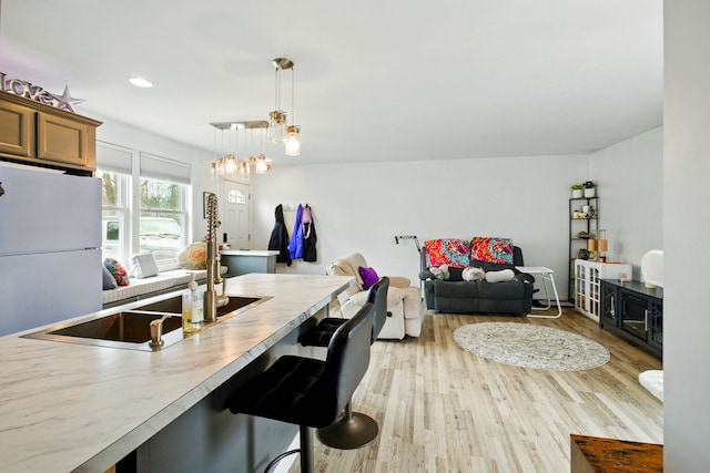 7330 Charlotte Rd, Lexington, MI 48450 - kitchen with pendant lighting, freestanding refrigerator, a breakfast bar area, and light wood-style floors