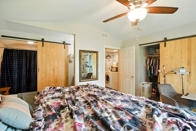 bedroom featuring washing machine and clothes dryer, visible vents, a barn door, a closet, and lofted ceiling
