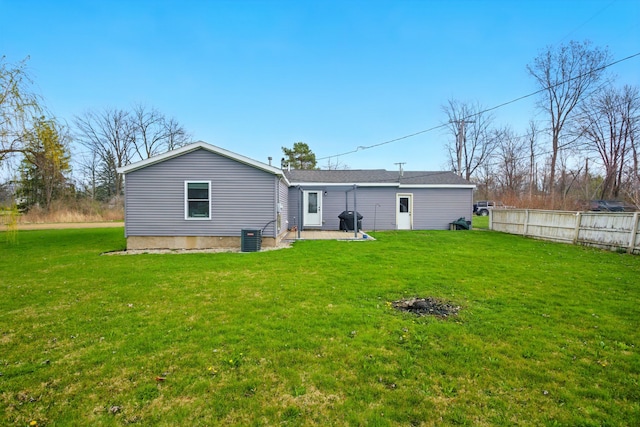 rear view of house with fence, a yard, a patio area, and central AC