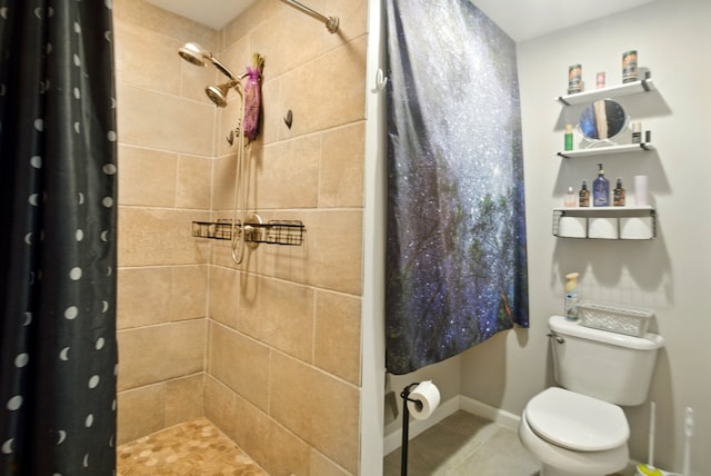 bathroom featuring tile patterned flooring, a tile shower, and toilet
