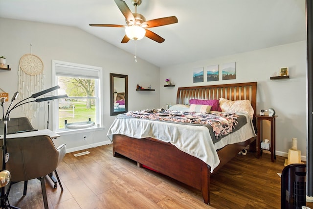 bedroom featuring a ceiling fan, visible vents, wood finished floors, baseboards, and lofted ceiling