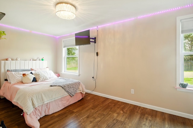 bedroom featuring baseboards, wood finished floors, and multiple windows
