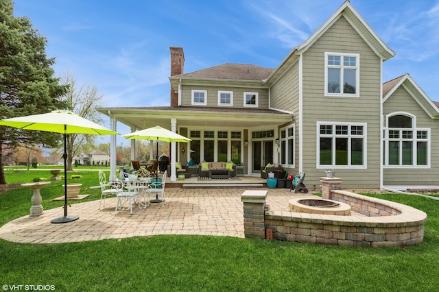 back of property with a patio, an outdoor living space with a fire pit, a lawn, and a chimney