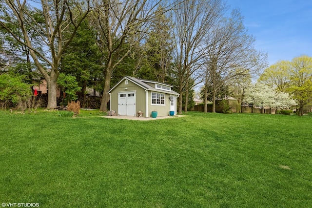view of yard with a detached garage, fence, and an outdoor structure