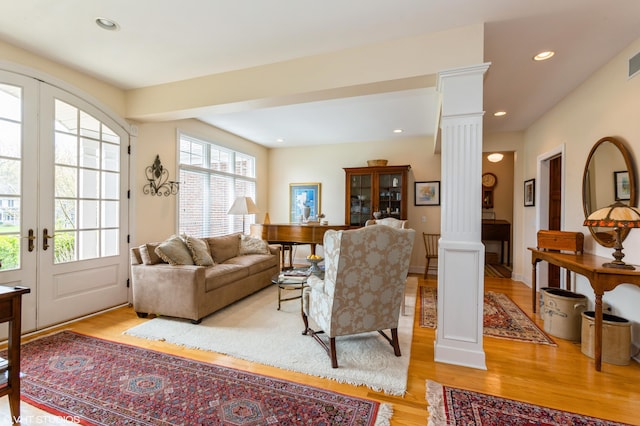 living room with ornate columns, recessed lighting, french doors, and light wood finished floors