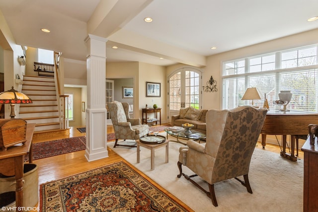 living room featuring stairs, recessed lighting, decorative columns, and light wood-style floors