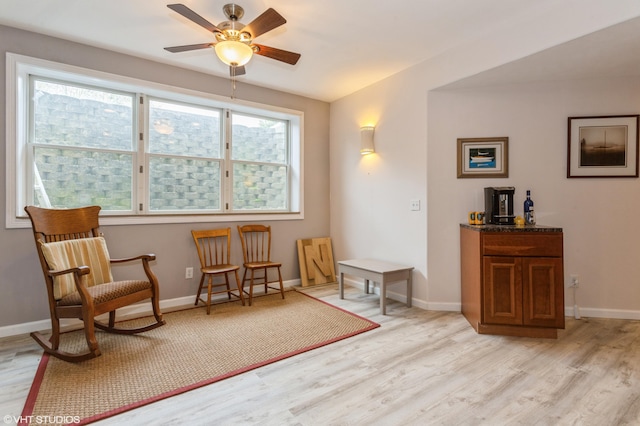 living area featuring light wood-style floors, a ceiling fan, and baseboards