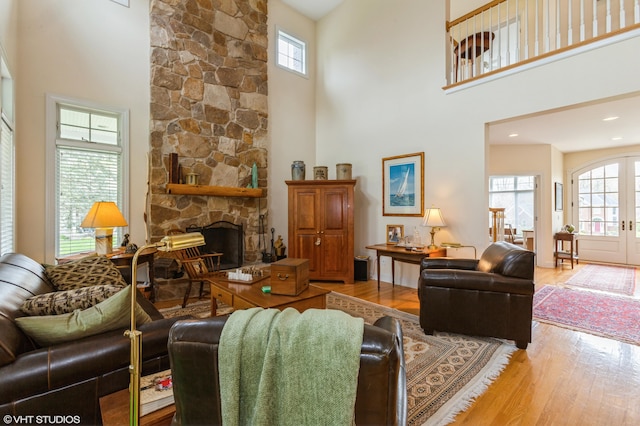 living room with a high ceiling, a stone fireplace, and wood finished floors
