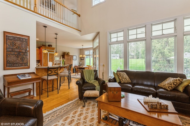 living room featuring an inviting chandelier, a high ceiling, and light wood finished floors