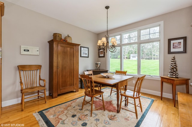 dining space featuring light wood-type flooring, baseboards, and an inviting chandelier