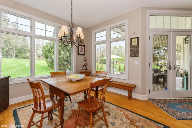 dining area featuring baseboards, a notable chandelier, a wealth of natural light, and light wood finished floors