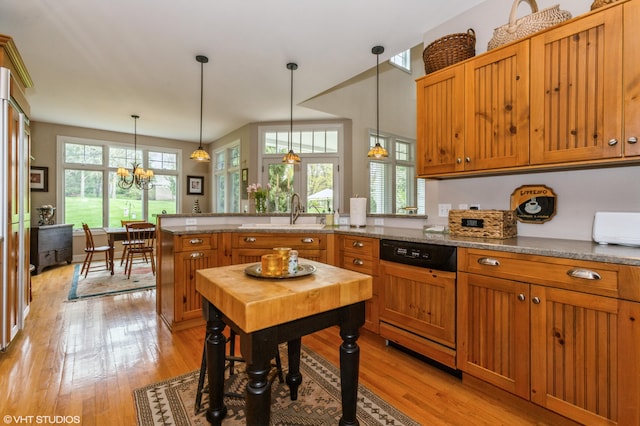 kitchen with paneled dishwasher, a sink, a peninsula, and a healthy amount of sunlight