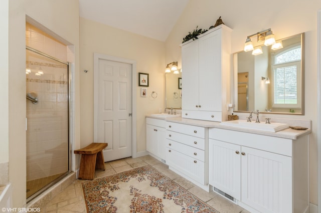 bathroom with a sink, a shower stall, double vanity, and lofted ceiling