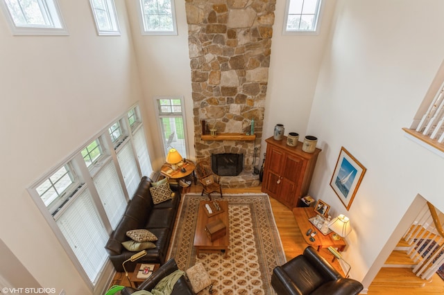 living area with a fireplace, wood finished floors, and a towering ceiling