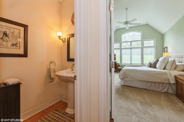 bedroom featuring baseboards, wood finished floors, lofted ceiling, and ensuite bath