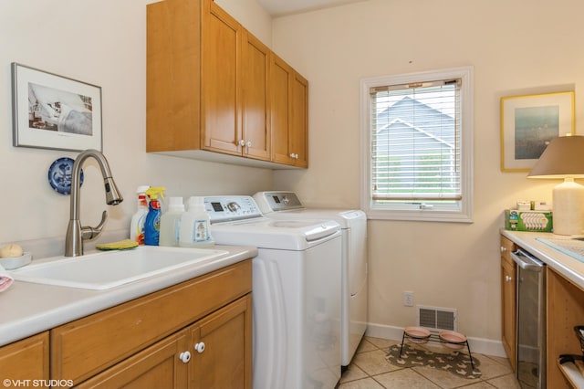 laundry area featuring visible vents, washer and dryer, a sink, cabinet space, and light tile patterned floors