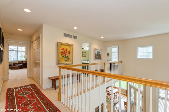 hall with visible vents, recessed lighting, plenty of natural light, and light carpet