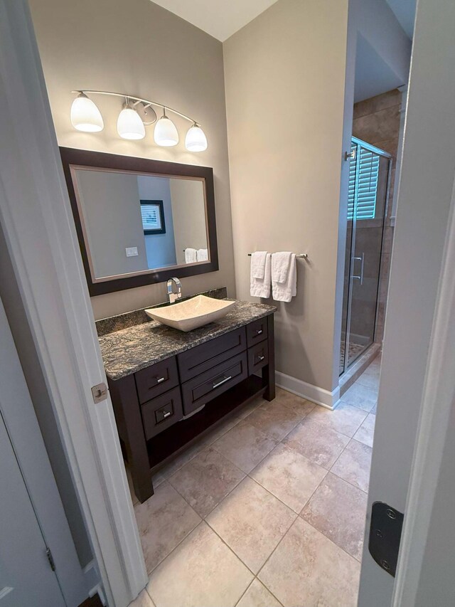 bathroom with tile patterned floors, a shower stall, baseboards, and vanity