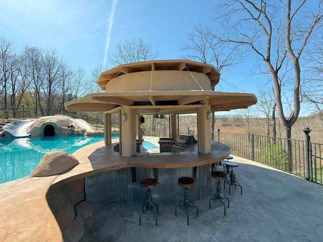 view of swimming pool featuring a grill, fence, outdoor dry bar, and a fenced in pool