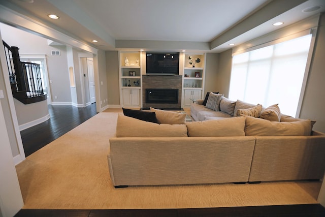 living room featuring a glass covered fireplace, recessed lighting, baseboards, wood finished floors, and visible vents