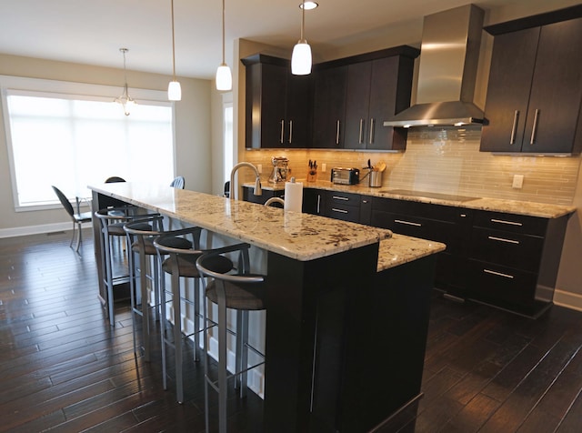 kitchen with a kitchen breakfast bar, baseboards, wall chimney exhaust hood, and dark wood-type flooring