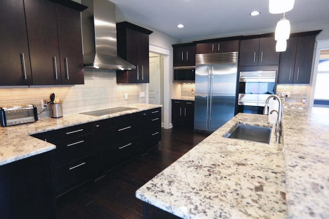 kitchen with decorative backsplash, a toaster, wall chimney range hood, a sink, and appliances with stainless steel finishes