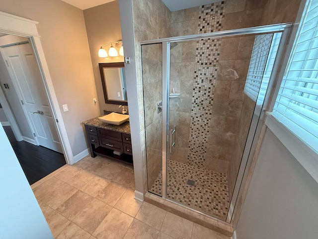 bathroom featuring vanity, tile patterned flooring, baseboards, and a stall shower