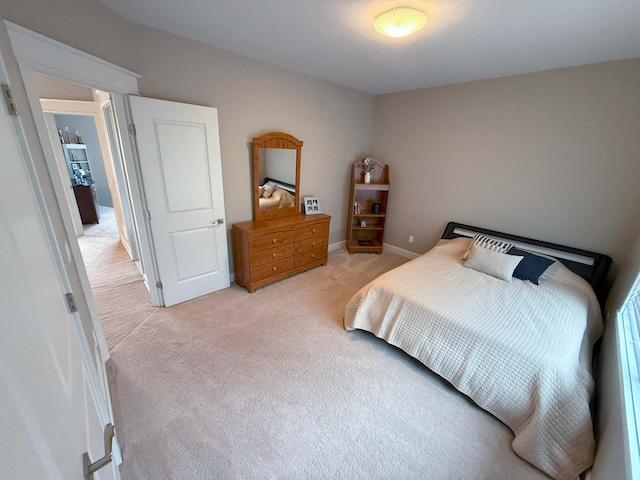 bedroom with light colored carpet and baseboards