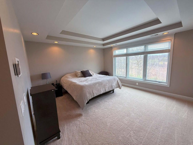 bedroom with visible vents, baseboards, light carpet, a tray ceiling, and recessed lighting