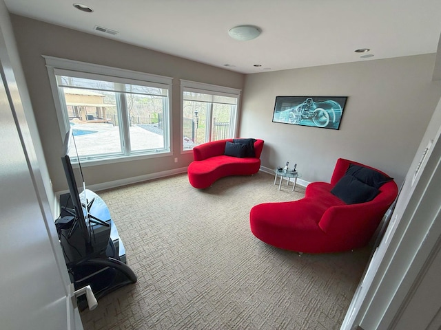 living area with visible vents, carpet flooring, baseboards, and plenty of natural light