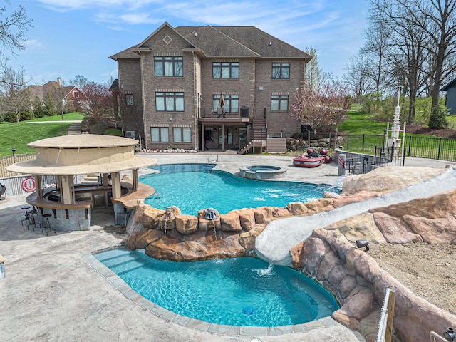 view of pool featuring fence, outdoor dry bar, a pool with connected hot tub, stairway, and a patio area