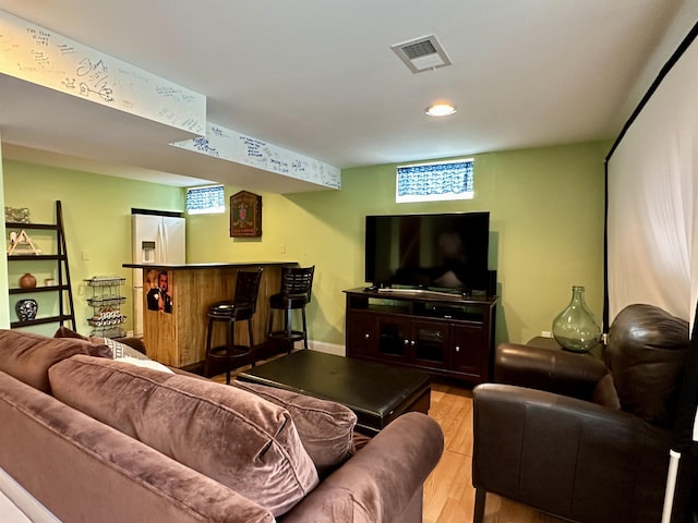 living area with visible vents, a dry bar, and light wood-style flooring