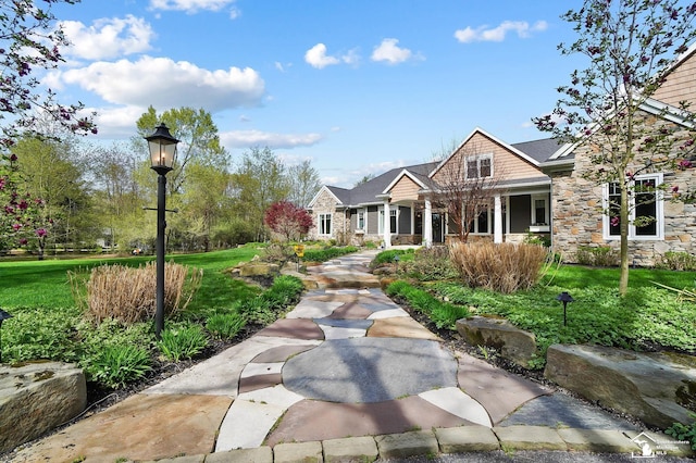 view of front of property with a porch, a front lawn, and stone siding