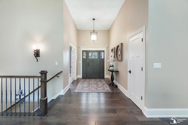 foyer entrance featuring baseboards, a high ceiling, and wood finished floors