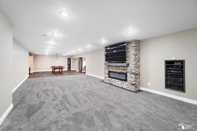 unfurnished living room with pool table, baseboards, dark carpet, and a stone fireplace