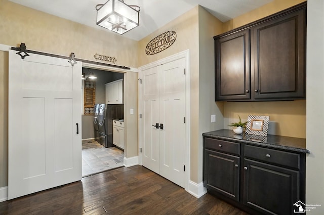 entrance foyer with washer / clothes dryer, baseboards, an inviting chandelier, and dark wood finished floors