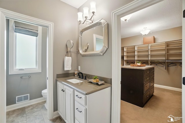 full bathroom featuring a sink, toilet, baseboards, two vanities, and visible vents