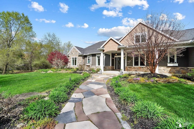 craftsman inspired home with a front yard, a porch, and stone siding