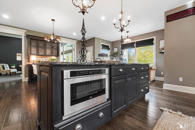 kitchen featuring dark wood-style flooring, dark countertops, a notable chandelier, baseboards, and a wealth of natural light