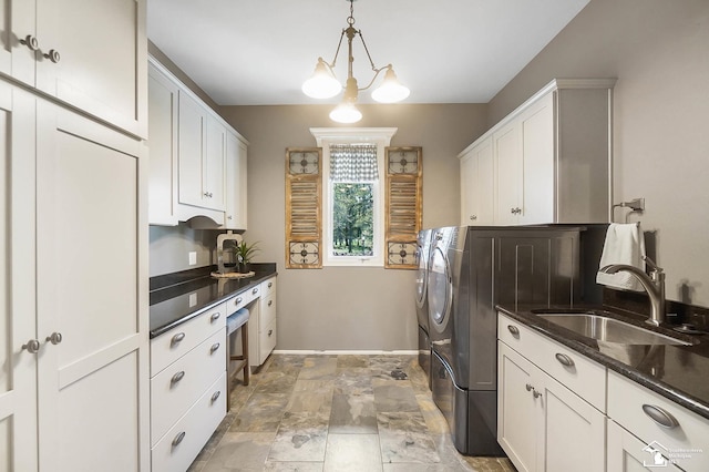 laundry area featuring washing machine and dryer, baseboards, stone finish floor, a sink, and cabinet space