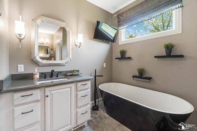 full bathroom featuring vanity, baseboards, and a freestanding bath