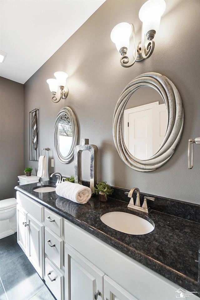 bathroom with double vanity, a sink, and toilet