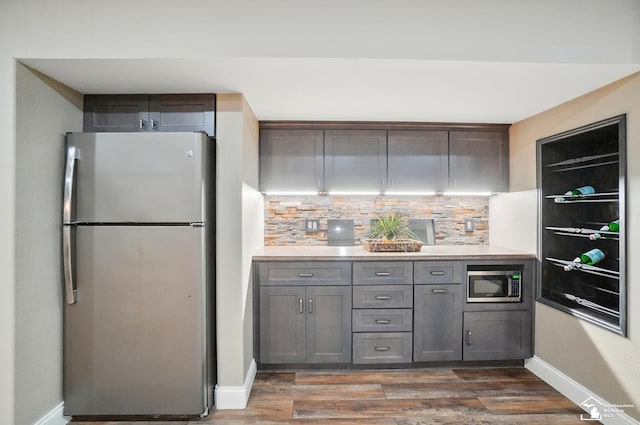 kitchen featuring decorative backsplash, dark wood finished floors, light countertops, baseboards, and stainless steel appliances