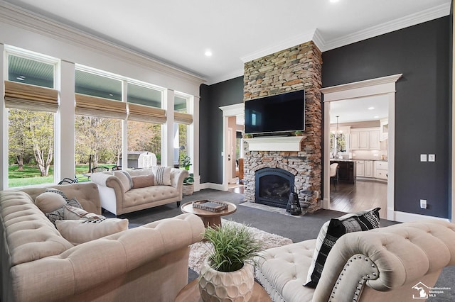 living area featuring crown molding, baseboards, recessed lighting, and a stone fireplace