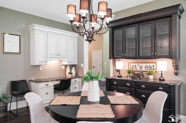 dining room featuring baseboards, wood finished floors, and a notable chandelier