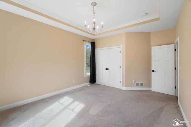 unfurnished bedroom with crown molding, a notable chandelier, light colored carpet, a tray ceiling, and visible vents
