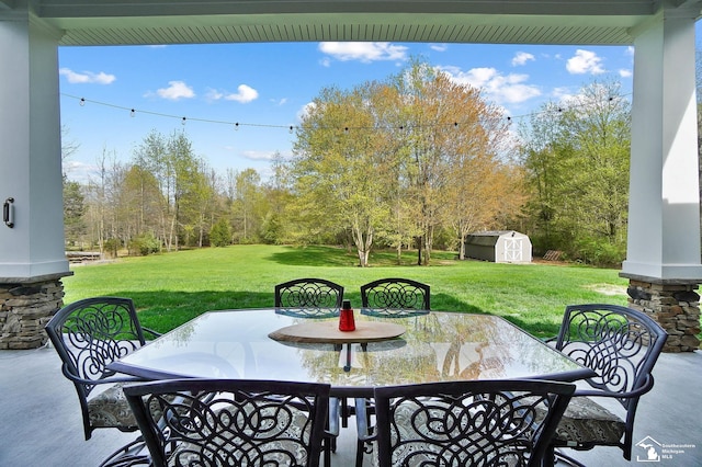 view of patio / terrace with outdoor dining area, an outbuilding, and a storage unit