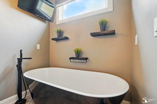bathroom featuring a freestanding tub and baseboards
