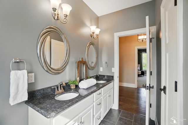 bathroom featuring a sink, baseboards, tile patterned flooring, and double vanity
