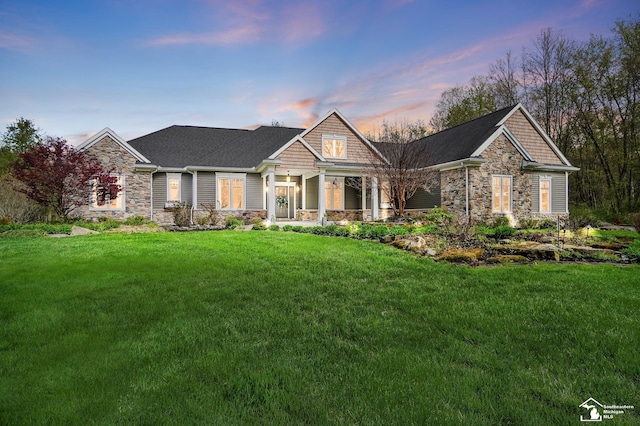 craftsman-style home with covered porch, a front yard, and stone siding